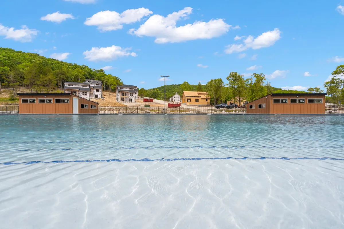A stunning view of waterfront cabins alongside clear, sparkling water and scenic hills. The scene is tranquil at sunset, with hints of fishing and boating opportunities, all surrounded by untouched natural beauty.
