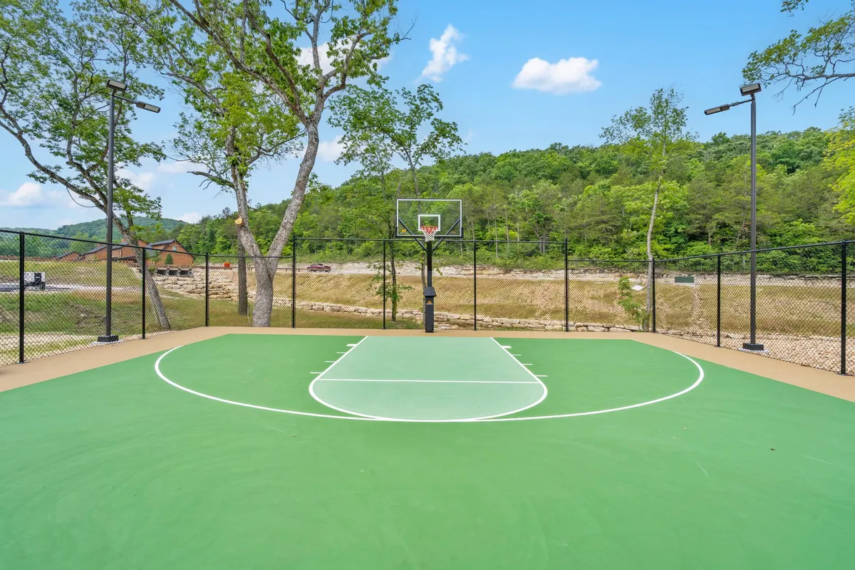 An active scene showing a basketball court nestled among trees, with a mountainous backdrop. The court is ready for friendly games and outdoor exercise, creating a playful and energetic atmosphere.